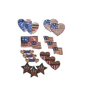 May include: A set of 10 iron-on patches featuring American flag designs. The patches include hearts, stars, and flags with red, white, and blue sequins. Some patches have the text "I Love" and "USA" printed on them.