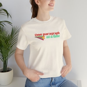 May include: White t-shirt with a colourful graphic of a shooting star and the text "One paragraph at a time".