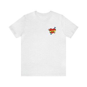 Puede incluir: Camiseta blanca con un diseño de tatuaje de corazón rojo y flecha. El corazón tiene una pancarta amarilla con la palabra "Mama" escrita en ella.
