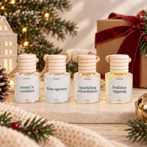 May include: Four small clear glass bottles with light wood screw caps and hanging cords. Each bottle contains liquid and a white label with the text 8Twelve, 8mL, and the scents Santa's Cookies, Blue Spruce, Sparkling Snowflakes, or Holiday Eggnog.