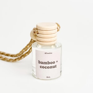 May include: A clear glass bottle with a wooden cap and a beige string. The bottle contains a liquid and has a label that reads "8Twelve bamboo + coconut 8mL".