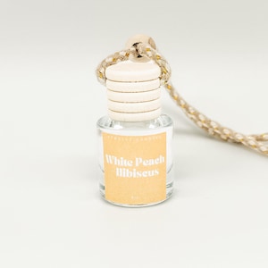 May include: A white peach hibiscus car air freshener with a brown label and a white string.