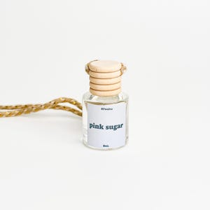 May include: A clear glass bottle with a wooden cap and a gold string. The bottle is labeled "STwelve pink sugar 8mL".