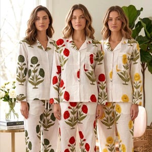 May include: Three women wearing matching white pajama sets with floral patterns. One set has green flowers, another has red flowers, and the third has yellow flowers. The pajamas include a button-down top and pants.