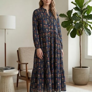 May include: A long, navy blue dress with a floral pattern. The dress has long sleeves, a mandarin collar, and a tiered skirt. The floral pattern includes red, brown, and peach-colored flowers and teardrop shapes.