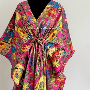 May include: A pink, blue, yellow, and green floral print kaftan with a V-neck and a tie at the waist. The print features images of women and birds. The text "TanzanitevsDiamond" is visible on the front of the kaftan.