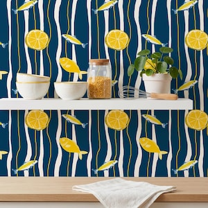 May include: A whimsical kitchen scene featuring a navy blue and white striped wallpaper adorned with yellow lemons and fish. A white shelf holds bowls, a jar of grains, and a potted plant. A wooden countertop is in the foreground.