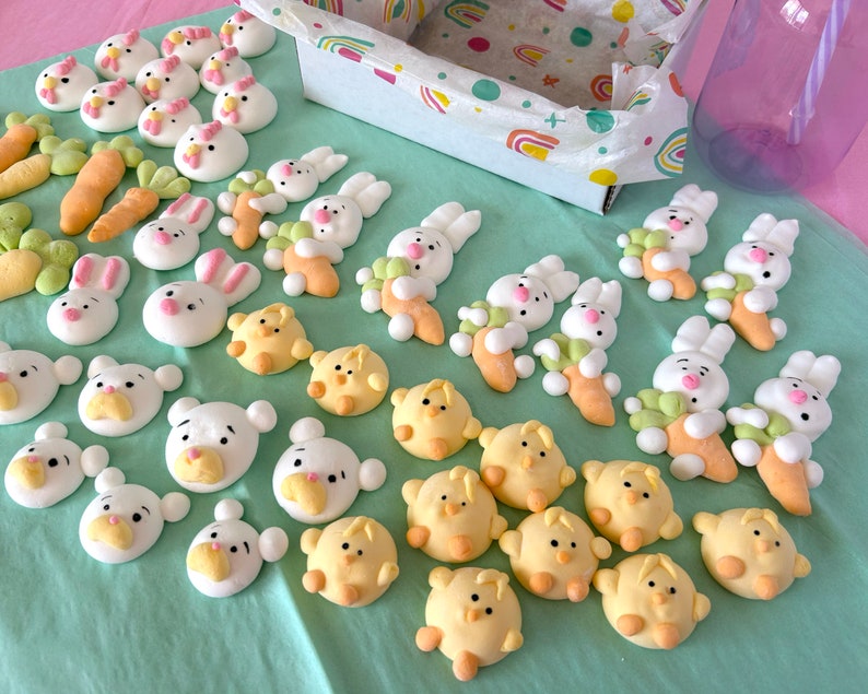 An assortment of charming marshmallow shaped like chicks, white bears, and pink-eared bunnies are presented in a box, accentuated by a colorful paper lining. A logo sticker on the box Marshmallow Pig and Bear, it delightful treat experience.