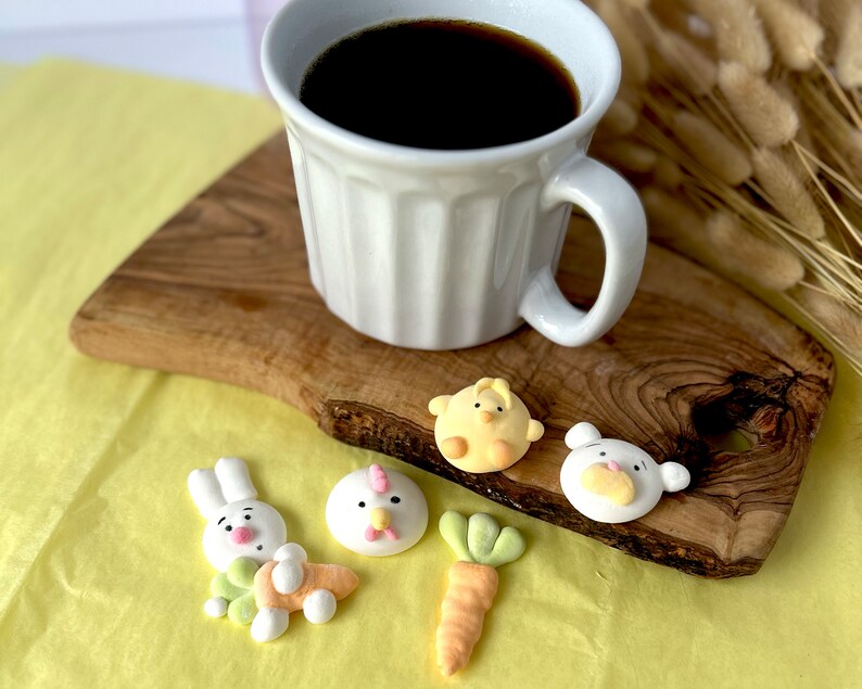 An assortment of charming marshmallow shaped like chicks, white bears, and pink-eared bunnies are presented in a box, accentuated by a colorful paper lining. A logo sticker on the box Marshmallow Pig and Bear, it delightful treat experience.