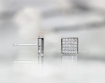 May include: A pair of silver-toned square stud earrings featuring a pavé setting with numerous small, clear, sparkling stones covering the entire front surface. The earrings include a standard post back mechanism for secure attachment to the earlobe.