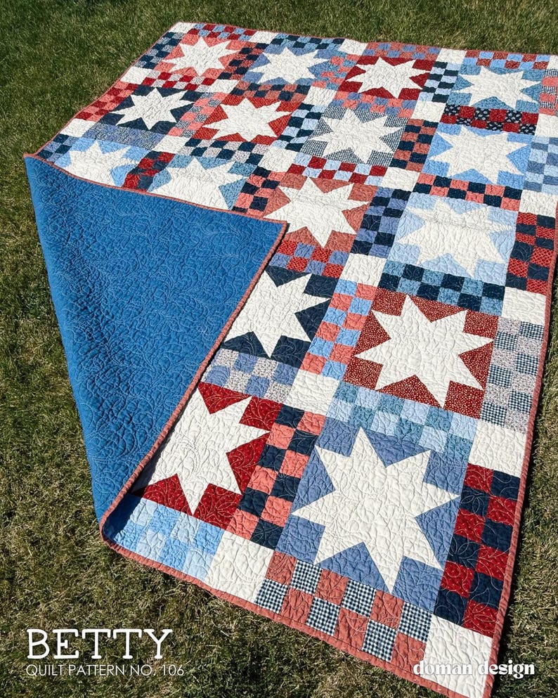 May include: A quilt featuring a repeating pattern of white stars set against a background of red, white, and blue checkered squares. The quilt has a solid blue backing with a quilted texture and a red border. Text reads: BETTY QUILT PATTERN NO. 106.