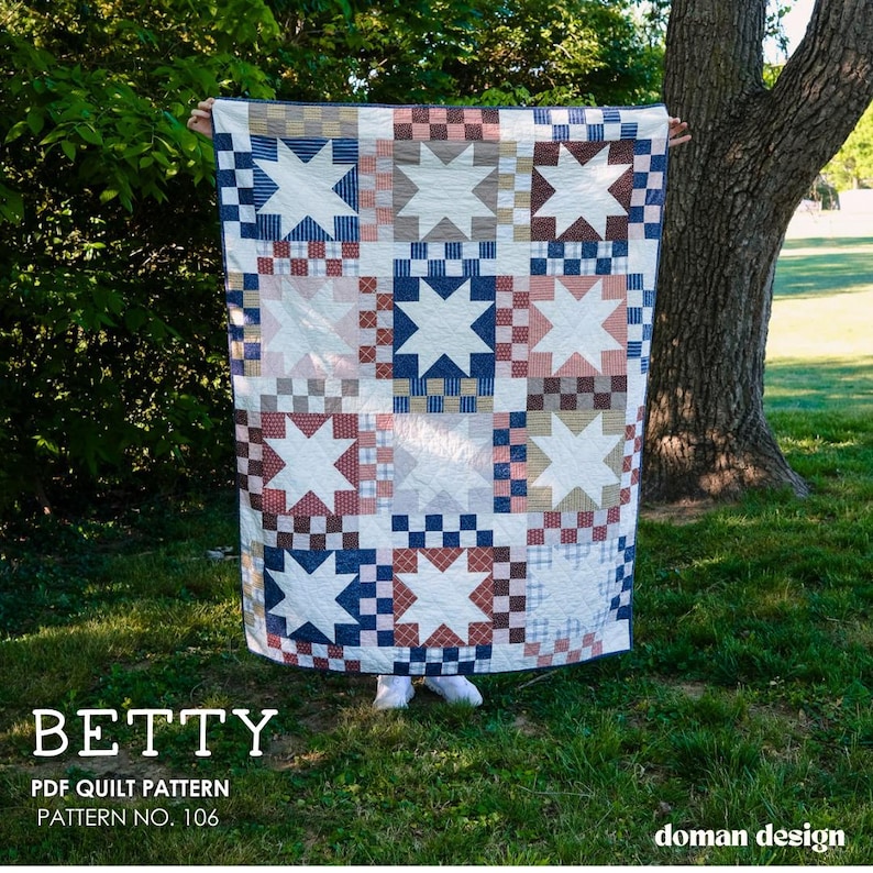 May include: A rectangular quilt featuring a repeating star block pattern in a grid layout. The quilt displays various fabric squares in shades of blue, tan, white, and muted red, arranged in a checkerboard style around white eight-pointed stars.