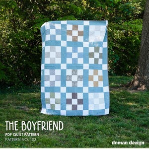 Pode incluir: Um edredom xadrez azul e branco com quadrados de várias cores, incluindo marrom, cinza e verde. O edredom é exibido ao ar livre com o texto "THE BOYFRIEND" e "PDF QUILT PATTERN PATTERN NO. 103".