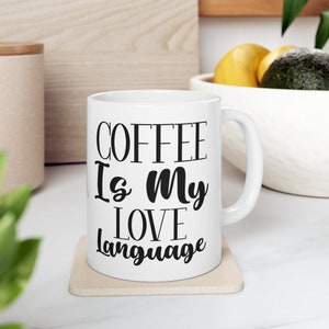 May include: White ceramic coffee mug with black text that reads "Coffee is my love language".