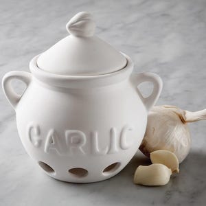 May include: A white ceramic garlic keeper with a lid and two handles. The word "GARLIC" is embossed on the front. A whole garlic bulb and two cloves are next to the keeper.