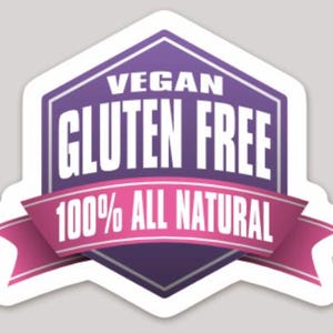 May include: A white sticker with a purple and pink design. The sticker has the words "VEGAN" and "GLUTEN FREE" in white, with "100% ALL NATURAL" on a pink ribbon.