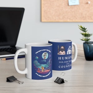 Può includere: Due tazze in ceramica bianca con manici blu. La tazza a sinistra ha uno sfondo blu con un astronauta dei cartoni animati nello spazio e il testo "Il cielo non è il limite, è solo l'inizio". La tazza a destra ha uno sfondo blu con un cartone animato di un uomo delle caverne che tiene una lancia e un astronauta. Il testo sulla tazza dice "Umani 300.000 anni e contando".
