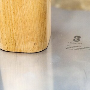 May include: Close-up of a wooden base with a light wood grain. The base is sitting on a silver surface with the text "LOOKURY Handmade in Vietnam Suitable material for SW Fitting Type: C18"