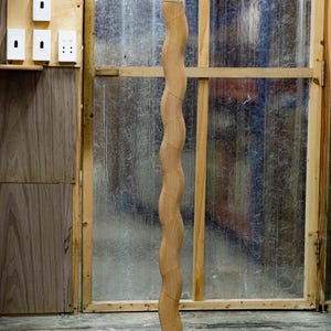 May include: A wooden floor lamp with a white globe shade. The lamp has a unique, wavy design and a black base.