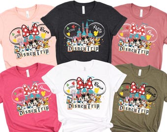 May include: Five pink, white, gray, green, and red t-shirts with a Disney Trip design. Each shirt features a Mickey Mouse head with a red bow, a castle, fireworks, and a group of Disney characters. The shirts are personalized with the names Beth, Philip, Alex, Amanda, Bella, and Jessie.