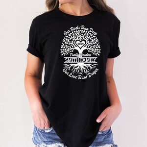 May include: Black t-shirt with a white tree design. The tree has a heart with the year 2024 inside. The text "Our Roots Run Deep" is above the tree, "Family Reunion" is below the tree, and "SMITH FAMILY" is in a banner below the text. The text "Our Love Runs Deeper" is below the roots of the tree.