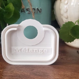 May include: White plastic tag with a round hole and the word "Melange" embossed on it.