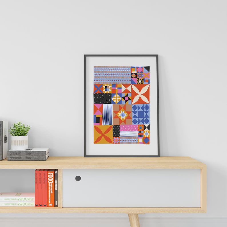 Puede incluir: Una impresi&oacute;n enmarcada de un patr&oacute;n geom&eacute;trico abstracto colorido con cuadrados, rect&aacute;ngulos y estrellas en tonos de rojo, naranja, azul, rosa y negro.