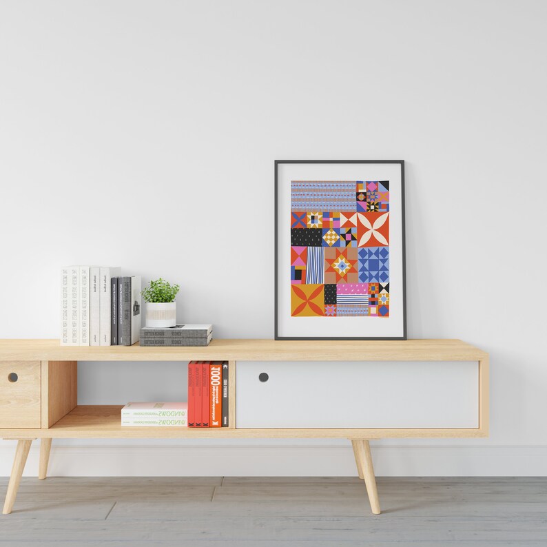 Puede incluir: Una consola de medios de madera de color marr&oacute;n claro con dos cajones y estantes abiertos. La consola tiene puertas blancas. Una impresi&oacute;n enmarcada con un patr&oacute;n geom&eacute;trico colorido cuelga en la pared sobre la consola. Los libros se muestran en los estantes y en los cajones.