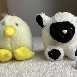 May include: Two plush toys: a yellow duck with a yellow beak and feet, and a white lamb with a black face and ears. A heart-shaped tag with the word "Puffkins" is attached to the lamb.