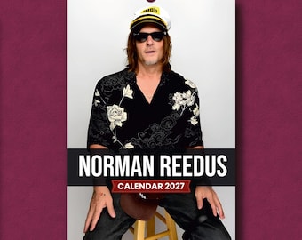 May include: A 2027 wall calendar featuring Norman Reedus. The cover displays a photograph of Norman Reedus wearing a white and yellow captain's hat, black sunglasses, and a black short-sleeved shirt with a white floral and cloud pattern.