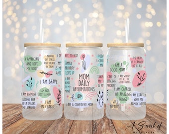 May include: Three glass tumblers with bamboo lids and straws, each adorned with colorful affirmations like "I am a good mom" and "I am brave." The tumblers feature floral and abstract designs, perfect for daily inspiration.