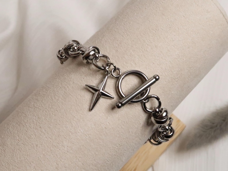 Puede incluir: Un brazalete de plata con cierre de palanca y un dije de estrella. El brazalete est&aacute; hecho de una cadena gruesa y robusta.