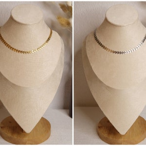 Puede incluir: Dos collares en expositores. Uno es dorado y el otro plateado. Ambos collares presentan una cadena de peque&ntilde;os eslabones en forma de flecha.