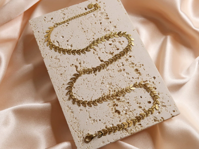 Puede incluir: Collar de cadena de hoja de oro con un dise&ntilde;o delicado. El collar est&aacute; hecho de peque&ntilde;as formas de hojas interconectadas.