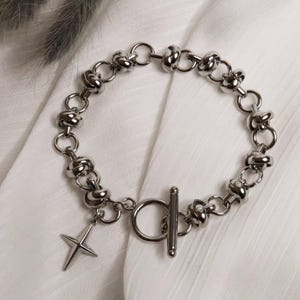 Puede incluir: Un brazalete de cadena de plata con un dije de estrella de plata y un cierre de palanca.