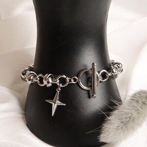 Puede incluir: Un brazalete de cadena de plata con un dije de estrella y un cierre de palanca.