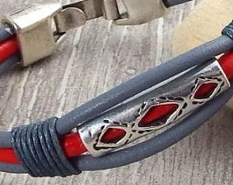 May include: A grey and red leather bracelet with a silver metal bead featuring a geometric design.