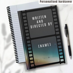 May include: A black and gray spiral bound notebook with a film strip design on the cover. The cover has the text "Written and Directed By [NAME]" on it.