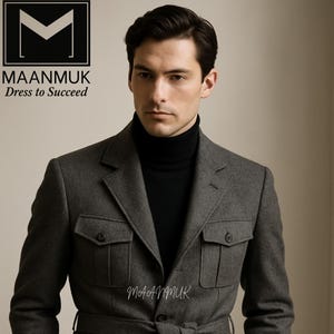 Puede incluir: Chaqueta gris con cinturón, cuatro bolsillos delanteros y un cuello alto negro. La chaqueta tiene el texto "MAANMUK Dress to Succeed" en la esquina superior izquierda y el nombre de la marca. La chaqueta es parte de un traje.