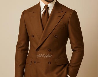 May include: A brown double-breasted suit with a matching tie and white dress shirt. The suit features a notched lapel and a classic fit. The brand logo and text "MAANMUK Dress to Succeed" are visible in the upper left corner.