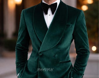 May include: A dark green velvet double-breasted blazer with a black satin lapel, worn with a black bow tie and a white dress shirt. The blazer has a classic, tailored fit.