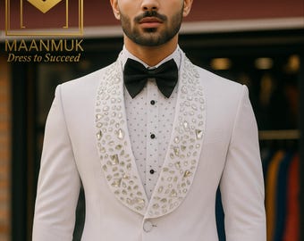 Puede incluir: Un esmoquin gris claro con pajarita negra. Las solapas de la chaqueta están adornadas con cristales brillantes. La camisa debajo tiene un sutil estampado de puntos. La imagen incluye el texto "MAANMUK Dress to Succeed".