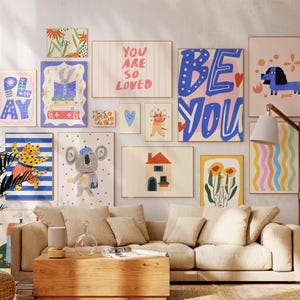 K&ouml;nnte beinhalten: Eine Sammlung gerahmter Kunstdrucke mit verschiedenen Designs, darunter ein blauer Dackel, ein Koala, ein Haus und die Worte "YOU ARE SO LOVED" und "BE YOU". Die Drucke sind in einer Vielzahl von Farben und Stilen gehalten und bilden eine lebendige und vielseitige Galeriewand.