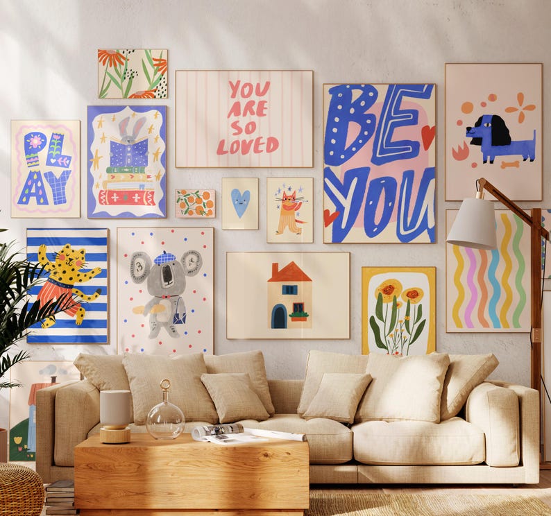 K&ouml;nnte beinhalten: Eine Sammlung gerahmter Kunstdrucke mit verschiedenen Designs, darunter ein blauer Dackel, ein Koala, ein Haus und die Worte "YOU ARE SO LOVED" und "BE YOU". Die Drucke sind in einer Vielzahl von Farben und Stilen gehalten und bilden eine lebendige und vielseitige Galeriewand.