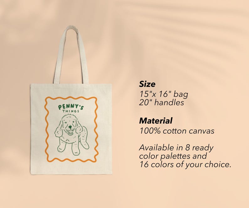 May include: A cream-colored cotton canvas tote bag with two handles. The front features a dark green line drawing of a dog inside an orange wavy-edged rectangular frame, with the text PENNY'S THINGS. Text lists size as 15"x 16" bag, 20" handles.
