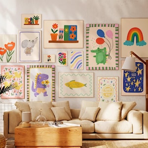 May include: A collection of colorful, framed art prints featuring whimsical illustrations. The artwork includes a rainbow, flowers, an elephant, a dinosaur, and a fish. The prints are displayed above a beige sofa in a living room setting.