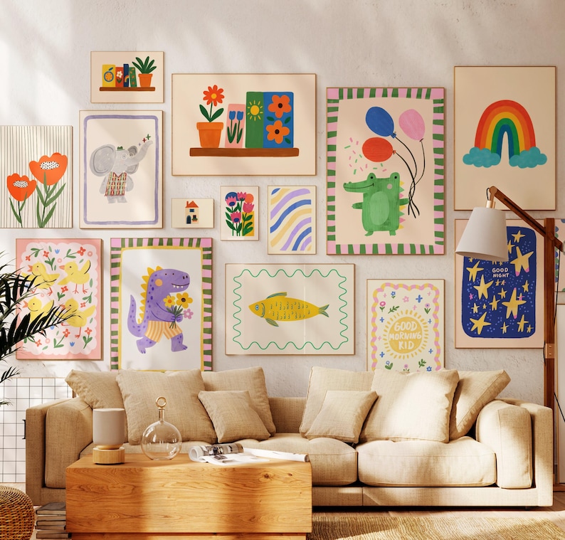 May include: A collection of colorful, framed art prints featuring whimsical illustrations. The artwork includes a rainbow, flowers, an elephant, a dinosaur, and a fish. The prints are displayed above a beige sofa in a living room setting.
