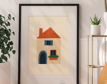 May include: Framed art print featuring a whimsical house illustration. The house has a red roof, blue shutters, and a blue arched doorway. The artwork is set against a cream background and framed in black.