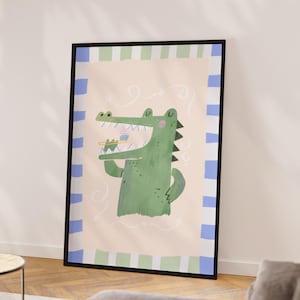 May include: A framed art print featuring a green cartoon alligator brushing its teeth. The artwork has a light pink background with a striped border in blue and green. Whimsical swirls and details add to the playful design.