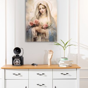 Pode incluir: Uma pintura da Virgem Maria segurando um buqu&ecirc; de rosas cor-de-rosa. Ela est&aacute; vestida com uma t&uacute;nica azul e branca e tem uma aur&eacute;ola acima da cabe&ccedil;a.